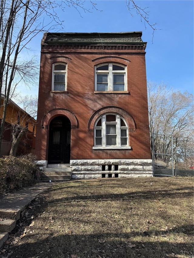 view of front of property with a gate, fence, and brick siding