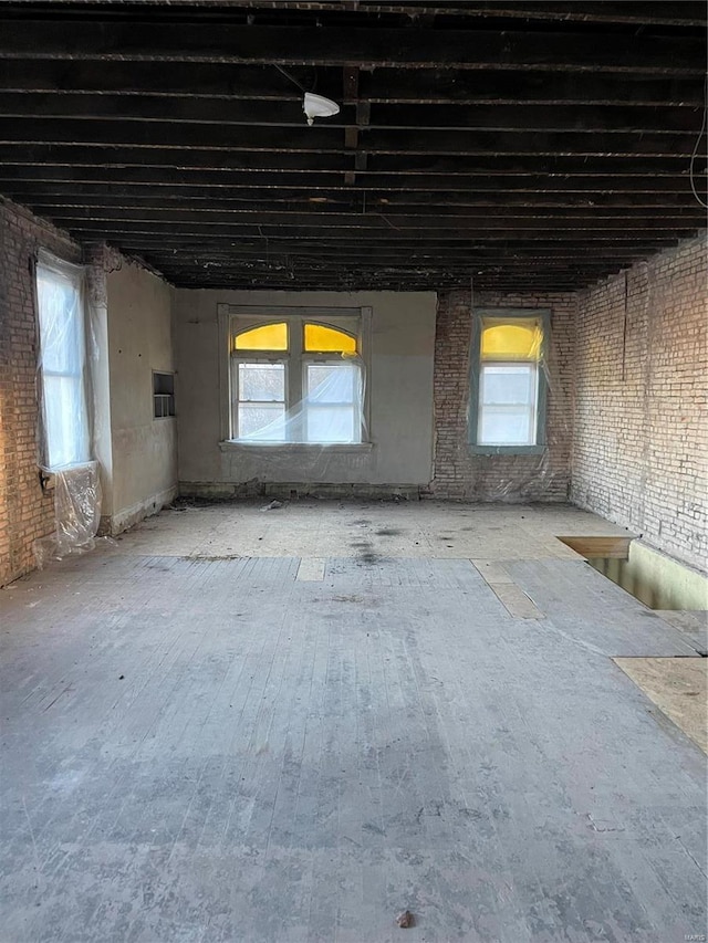 miscellaneous room with wood finished floors and brick wall