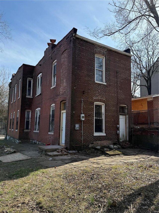 rear view of house featuring brick siding and a patio area