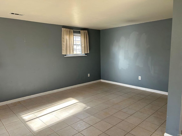 spare room featuring light tile patterned floors, visible vents, and baseboards