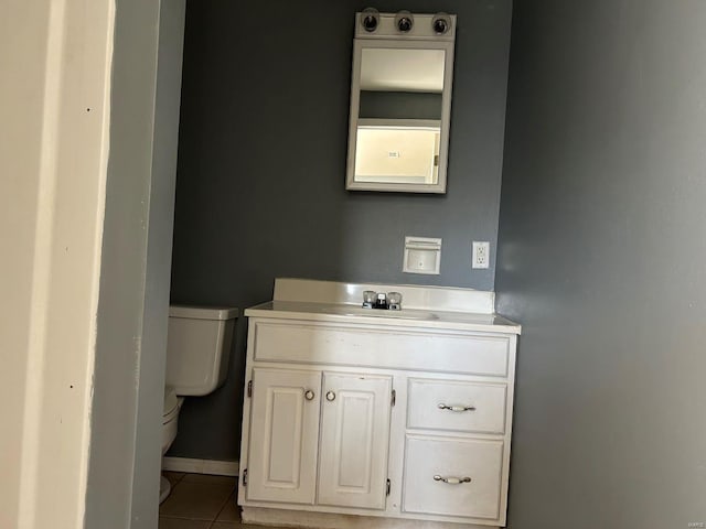 half bath featuring tile patterned floors, baseboards, toilet, and vanity