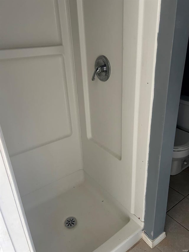 bathroom featuring toilet, a shower stall, and tile patterned flooring