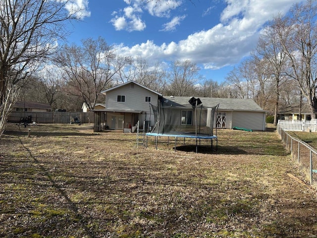 rear view of property featuring a fenced backyard and a trampoline