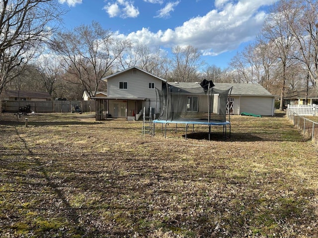 back of house featuring a trampoline and a fenced backyard