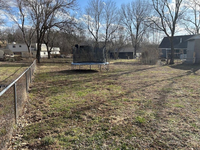 view of yard featuring a trampoline and fence