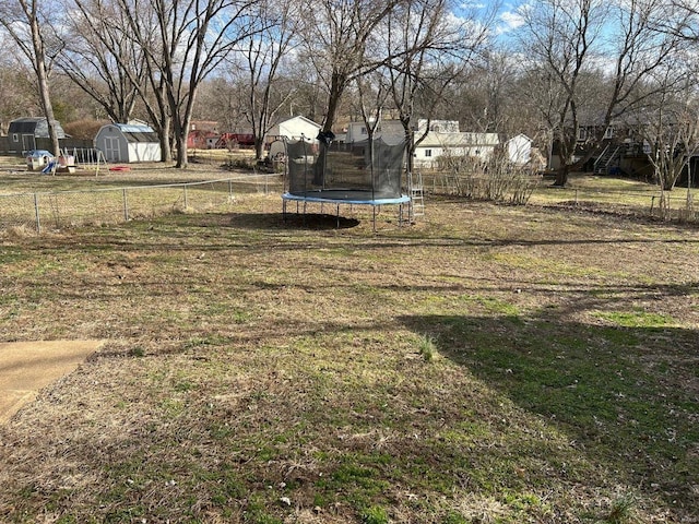 view of yard featuring an outdoor structure, a trampoline, fence, and a shed