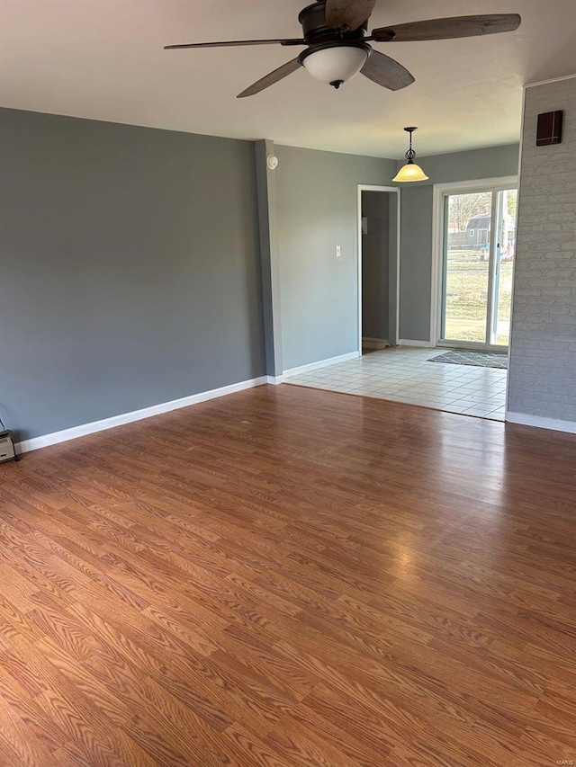 empty room featuring ceiling fan, baseboards, and wood finished floors