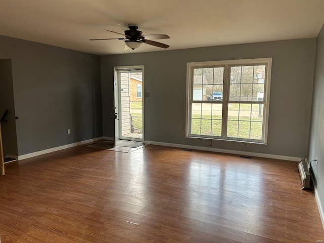 empty room with visible vents, ceiling fan, baseboards, and wood finished floors