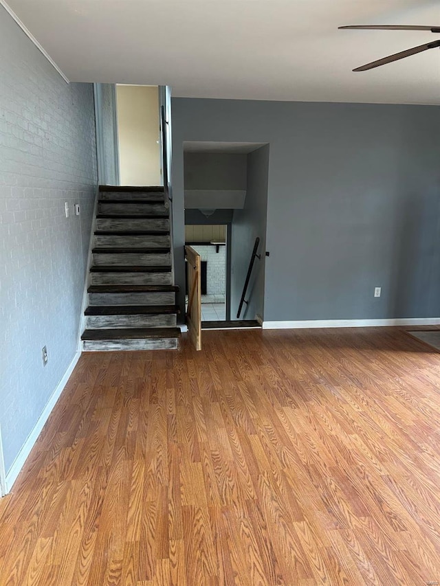 staircase featuring a ceiling fan, baseboards, and wood finished floors