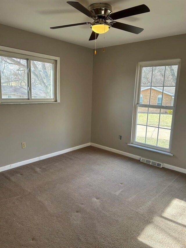 carpeted empty room featuring plenty of natural light, visible vents, and baseboards