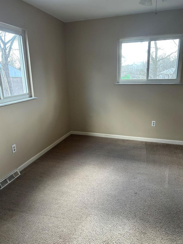 carpeted spare room featuring visible vents and baseboards