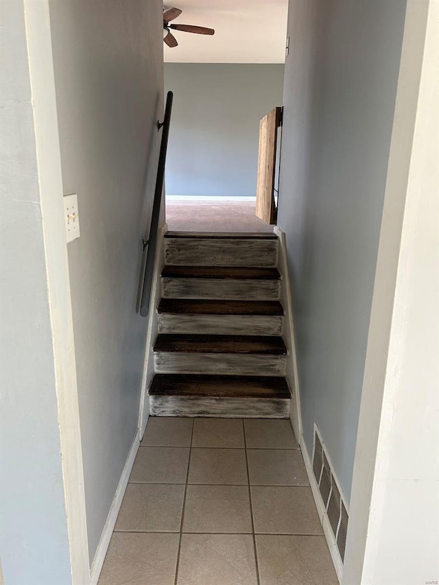 stairs with tile patterned floors, visible vents, baseboards, and a ceiling fan