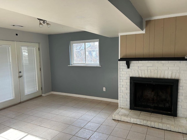 unfurnished living room featuring light tile patterned floors, french doors, baseboards, and a brick fireplace