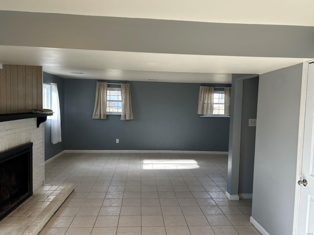 below grade area featuring light tile patterned floors, baseboards, and a fireplace