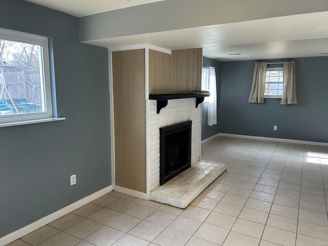 unfurnished living room with light tile patterned floors, a fireplace, and baseboards