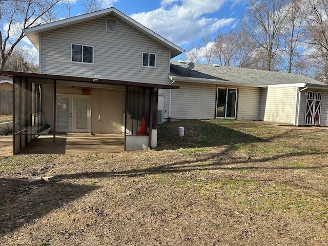 rear view of property featuring a lawn, french doors, a patio, and a sunroom