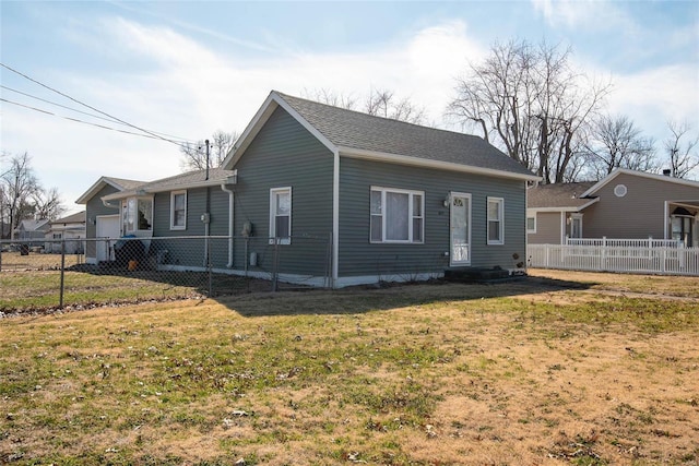 view of front of house featuring a front lawn, entry steps, fence, roof with shingles, and an attached garage