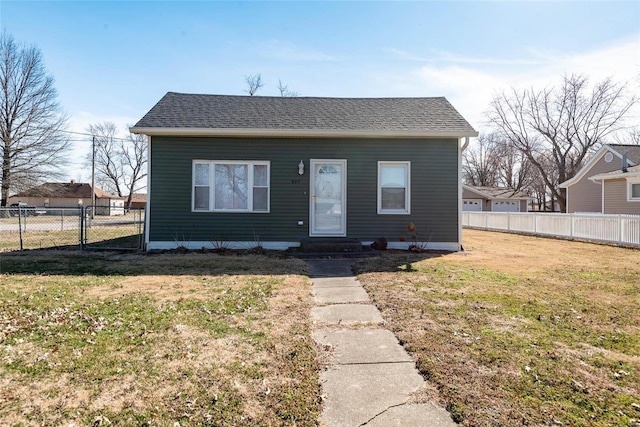 bungalow-style home with entry steps, roof with shingles, a front yard, and fence