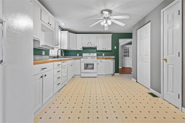 kitchen featuring a ceiling fan, a sink, white gas range oven, under cabinet range hood, and white cabinetry