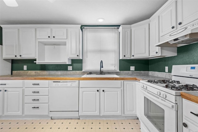 kitchen featuring under cabinet range hood, light floors, white cabinets, white appliances, and a sink