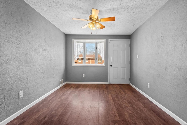 unfurnished bedroom with wood finished floors, a textured wall, visible vents, and baseboards