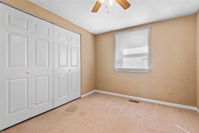 unfurnished bedroom with a ceiling fan, baseboards, visible vents, a closet, and light carpet