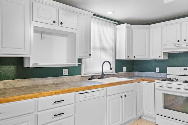 kitchen with under cabinet range hood, white appliances, white cabinets, and a sink