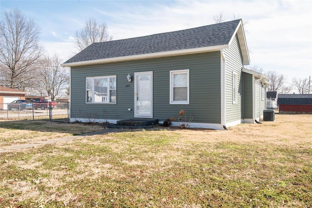 bungalow with a shingled roof, a front yard, and fence