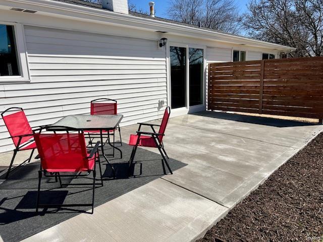 view of patio featuring outdoor dining space, fence, and visible vents