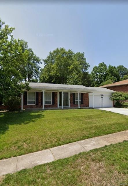 ranch-style home featuring brick siding, a garage, a front lawn, and driveway