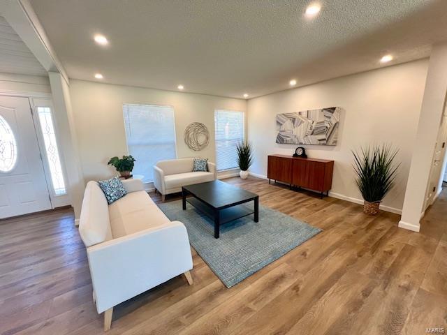 living area featuring recessed lighting, a textured ceiling, baseboards, and wood finished floors