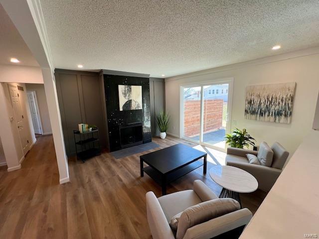 living area featuring a fireplace, recessed lighting, wood finished floors, and a textured ceiling