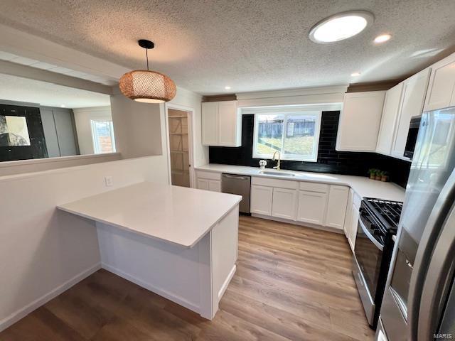 kitchen with white cabinetry, light wood-style floors, appliances with stainless steel finishes, and a sink