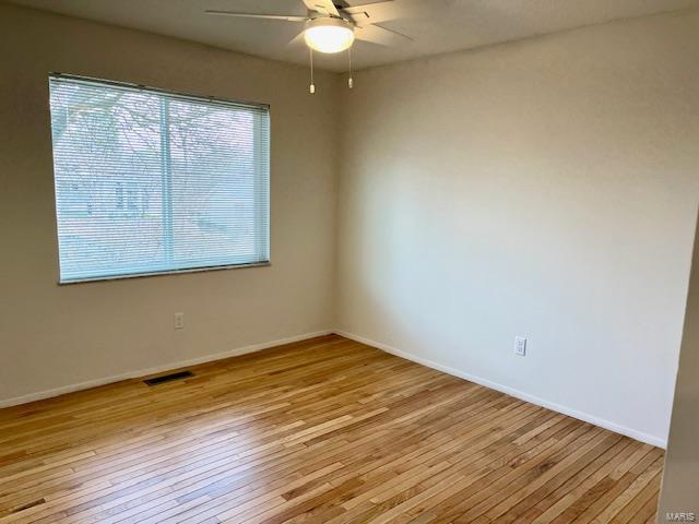 unfurnished room featuring light wood-style flooring, a ceiling fan, visible vents, and baseboards