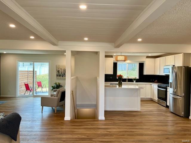 kitchen featuring white cabinetry, beamed ceiling, gas stove, and stainless steel refrigerator with ice dispenser