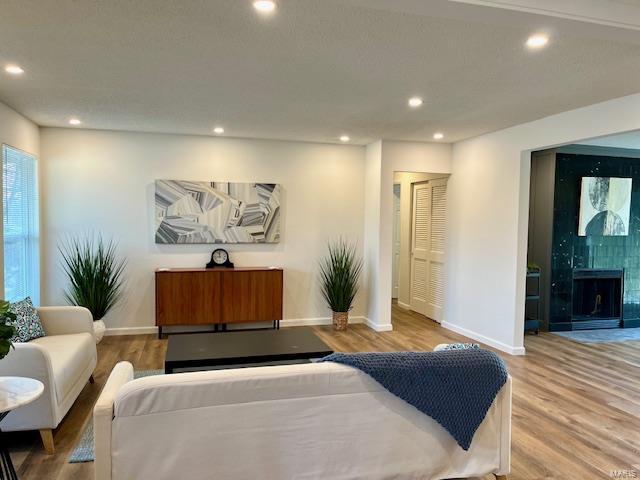 living area featuring a fireplace, recessed lighting, wood finished floors, and baseboards