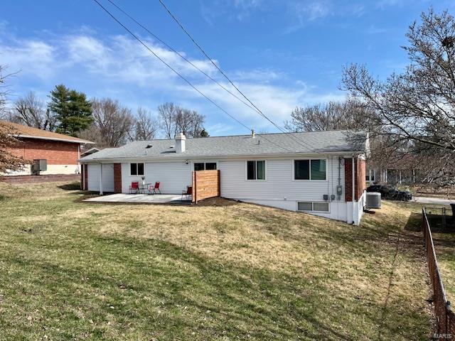 rear view of house featuring central air condition unit, a lawn, and a patio