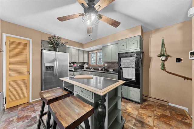 kitchen with tasteful backsplash, stone finish flooring, baseboards, stainless steel fridge, and dobule oven black