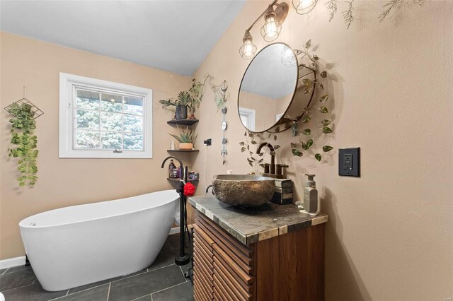 full bath featuring vanity, tile patterned floors, baseboards, and a freestanding bath