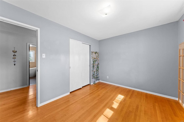 unfurnished bedroom featuring a closet, baseboards, and light wood-style flooring