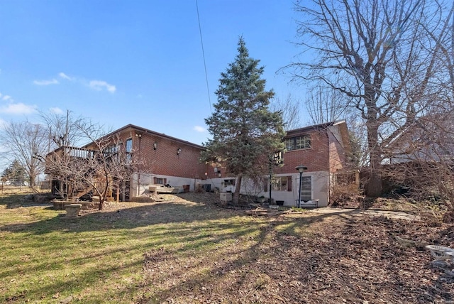 rear view of house with brick siding, stairway, a lawn, and a wooden deck