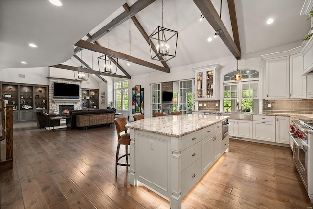 kitchen with white cabinets, a fireplace, a chandelier, range with two ovens, and a kitchen island