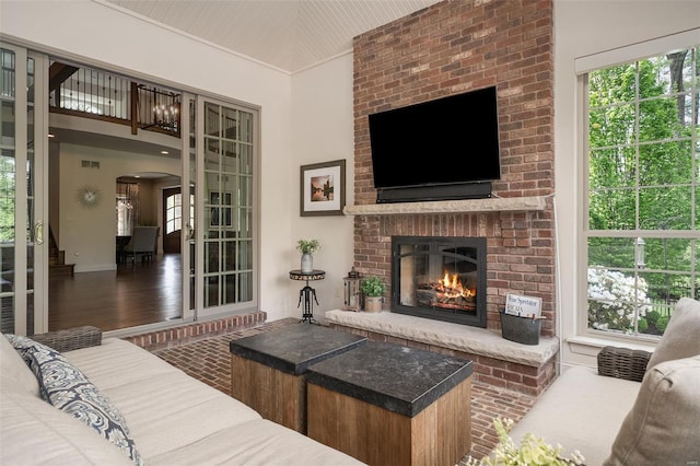 living area featuring visible vents, a fireplace, baseboards, brick floor, and arched walkways