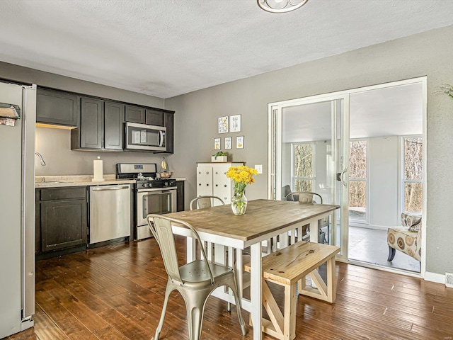 dining space featuring baseboards, a textured ceiling, and dark wood-style flooring