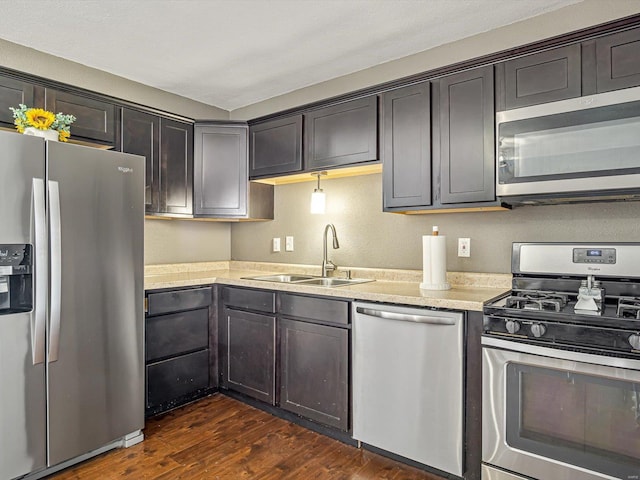 kitchen featuring dark wood finished floors, dark brown cabinetry, appliances with stainless steel finishes, and a sink