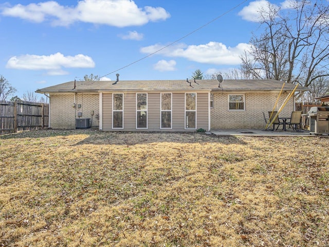 back of house with brick siding, fence, central AC unit, a lawn, and a patio