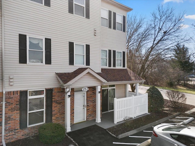 townhome / multi-family property with brick siding and roof with shingles