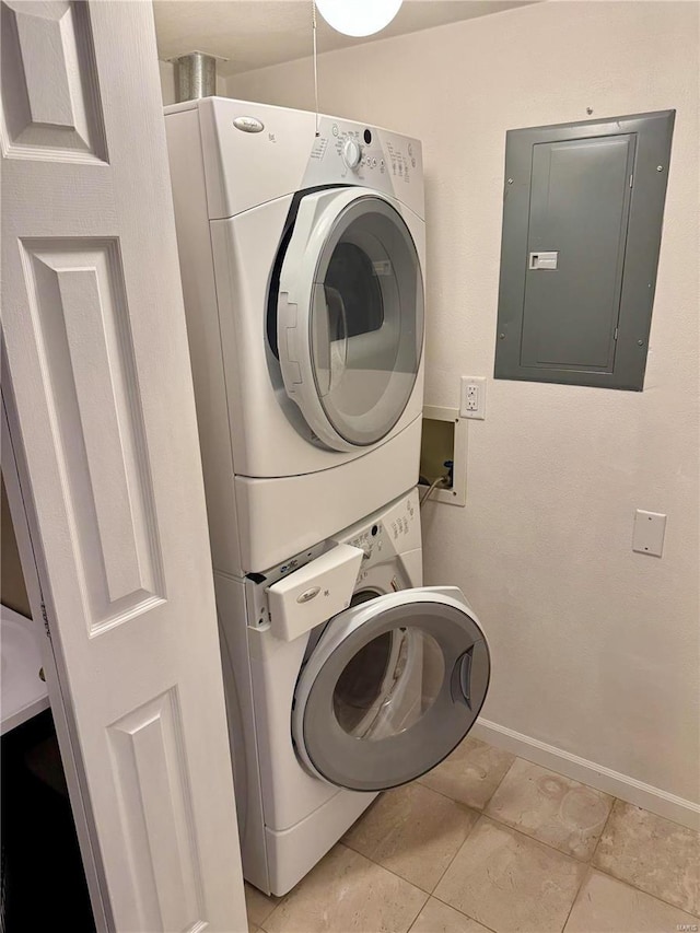 laundry room with electric panel, stacked washer / drying machine, baseboards, and tile patterned floors