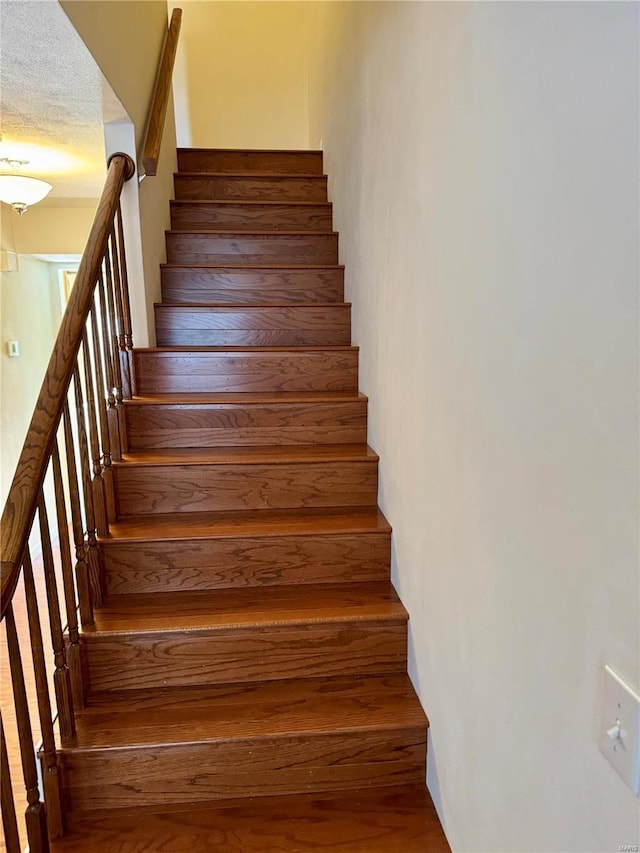 stairs with a textured ceiling