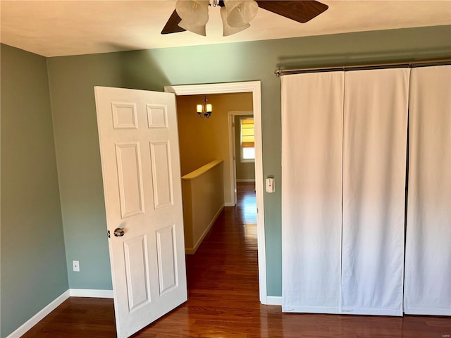 corridor featuring baseboards and dark wood-style flooring